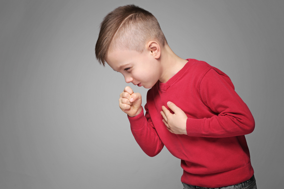 Little Boy Coughing on Gray Background